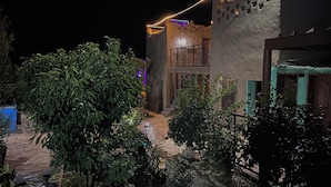 Un bâtiment doté d’un balcon, d’un mur en pierre et d’un arbre au premier plan.