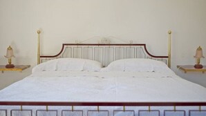 Ein Bett mit Holzrahmen und einem Kopfteil mit dekorativer Gestaltung. An beiden Seiten des Bettes stehen Nachttische mit Lampen.