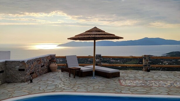 A pool area with lounge chairs and an umbrella, overlooking a scenic view of the sea and mountains. - "Villa Erifili" Luxurious villa with spectacular view in Skiathos Island (Taxiarchis)