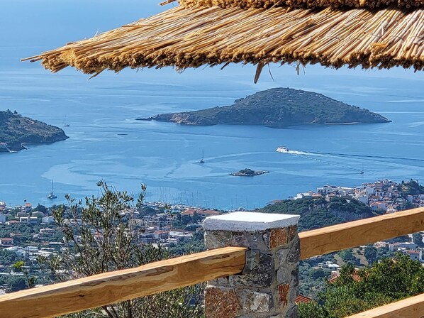 Une vue sur la côte, avec une construction au toit de chaume, une balustrade en pierre et une ville en arrière-plan.
