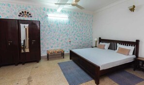 Relax in this serene bedroom with a large bed, a bench, and a wardrobe.