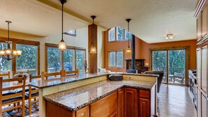Une cuisine spacieuse dotée de meubles en bois, de plans de travail en granit et de luminaires suspendus.