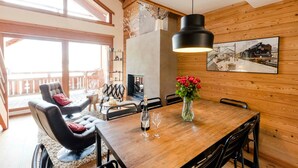 Um interior em madeira com uma mesa de jantar, cadeiras, um sofá e uma lareira.