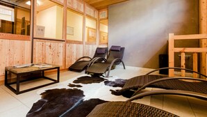 Uma sala de sauna com paredes de madeira, um tapete de couro de vaca e cadeiras reclináveis.