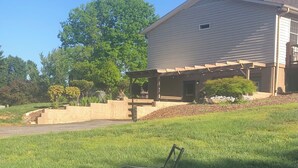 A house with a covered porch, a grassy yard, and a patio with chairs. - Cozy Suite on Cedars 1300sq ft (ONE LEVEL) (Hickory)