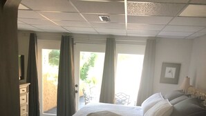 A bedroom with a bed, a dresser, a chair, and a door leading to an outdoor area. - Cozy Suite on Cedars 1300sq ft (ONE LEVEL) (Hickory)