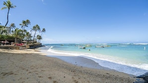 Uma praia com águas turquesa cristalinas, palmeiras e barcos.