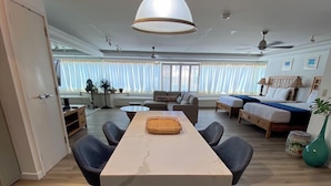 Uma sala de estar moderna com uma ilha de mesa de mármore, um sofá e uma área de jantar com cadeiras.