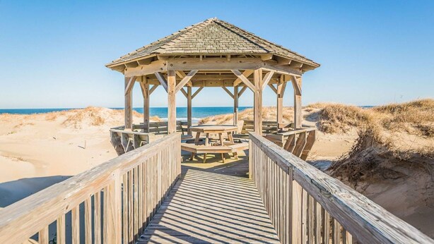 A wooden gazebo with a picnic table and benches, connected by a wooden walkway to the beach. - Bear Inn OBX - 4X4 Carova Beach, Oceanfront, Ocean View, Hot Tub, Pets OK (4X4 - Carova Beach)