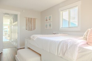 A bedroom with a bed, a window, and a door leading to another room. - Bear Inn OBX - 4X4 Carova Beach, Oceanfront, Ocean View, Hot Tub, Pets OK (4X4 - Carova Beach)