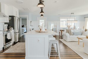 A modern kitchen with white cabinetry, stainless steel appliances, and a central island. - Bear Inn OBX - 4X4 Carova Beach, Oceanfront, Ocean View, Hot Tub, Gazebo (4X4 - Carova Beach)