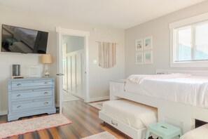 Une chambre à coucher avec un lit, une commode et un téléviseur fixé au mur.
