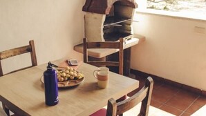 Ein Esstisch mit Stühlen, einer blauen Wasserflasche, einer Olivenplatte und einer Kaffeetasse.