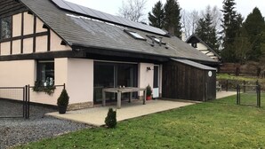 A modern house with a sloped roof, large windows, and a covered patio area.