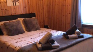 A wooden-paneled room with a bed, pillows, and a blanket.
