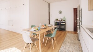 Uma cozinha moderna com uma mesa de madeira posta para o café da manhã, um espaço para vinhos e um relógio na parede.