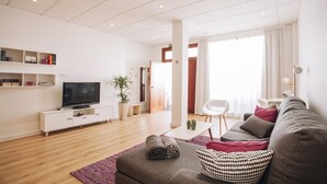 Uma sala de estar moderna com uma TV de tela plana, um sofá, uma mesa de centro e uma estante de livros.