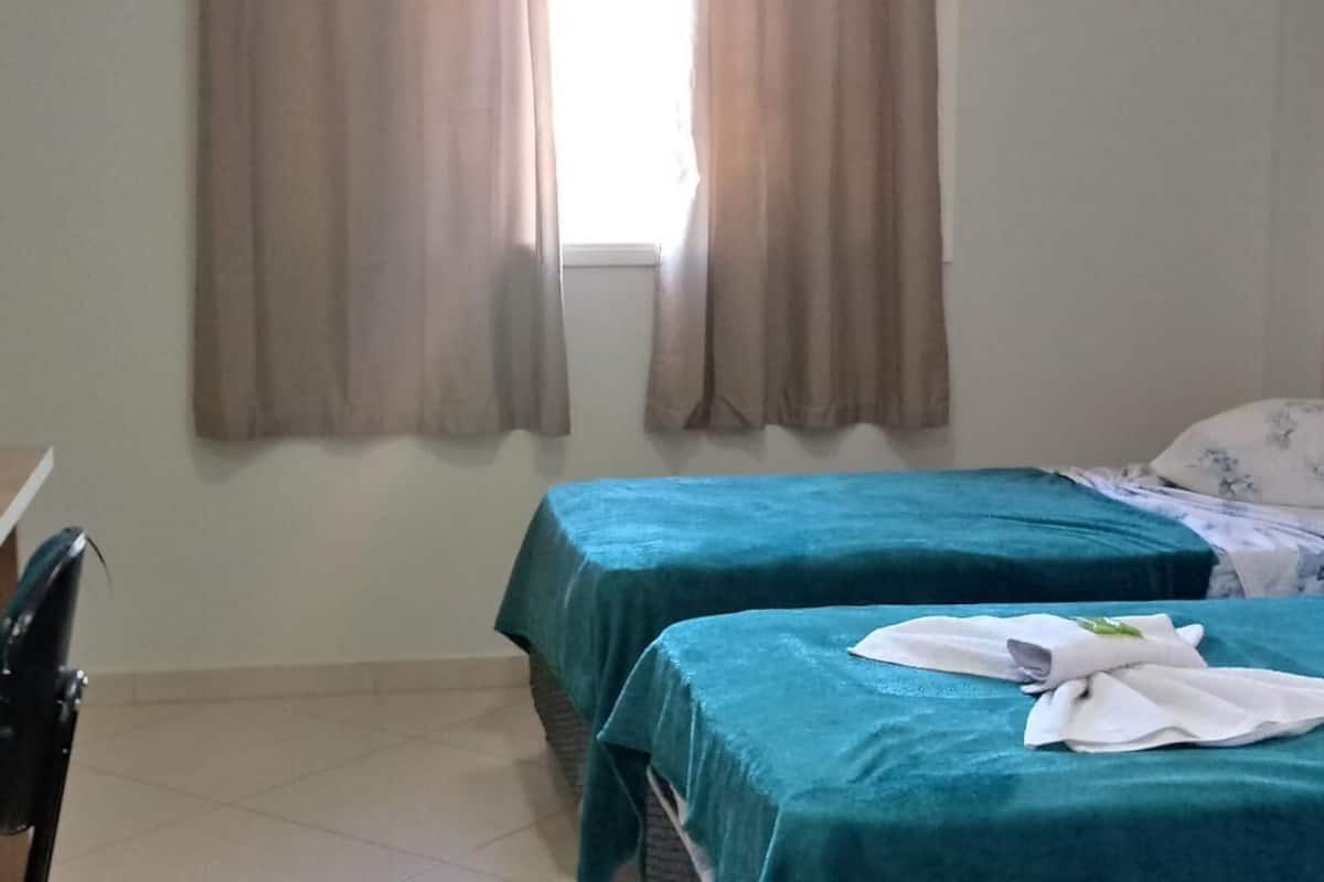 Una habitación con dos camas, un escritorio y una silla.