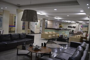 Un moderno vestíbulo de hotel con sofás de cuero, una mesa de centro y una lámpara colgante grande.