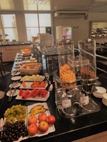 Un bufé con diversas opciones de comida, entre ellas frutas, cereales y postres.