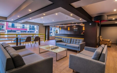 A modern hotel lobby with a sofa, armchairs, a coffee table, and a chessboard.