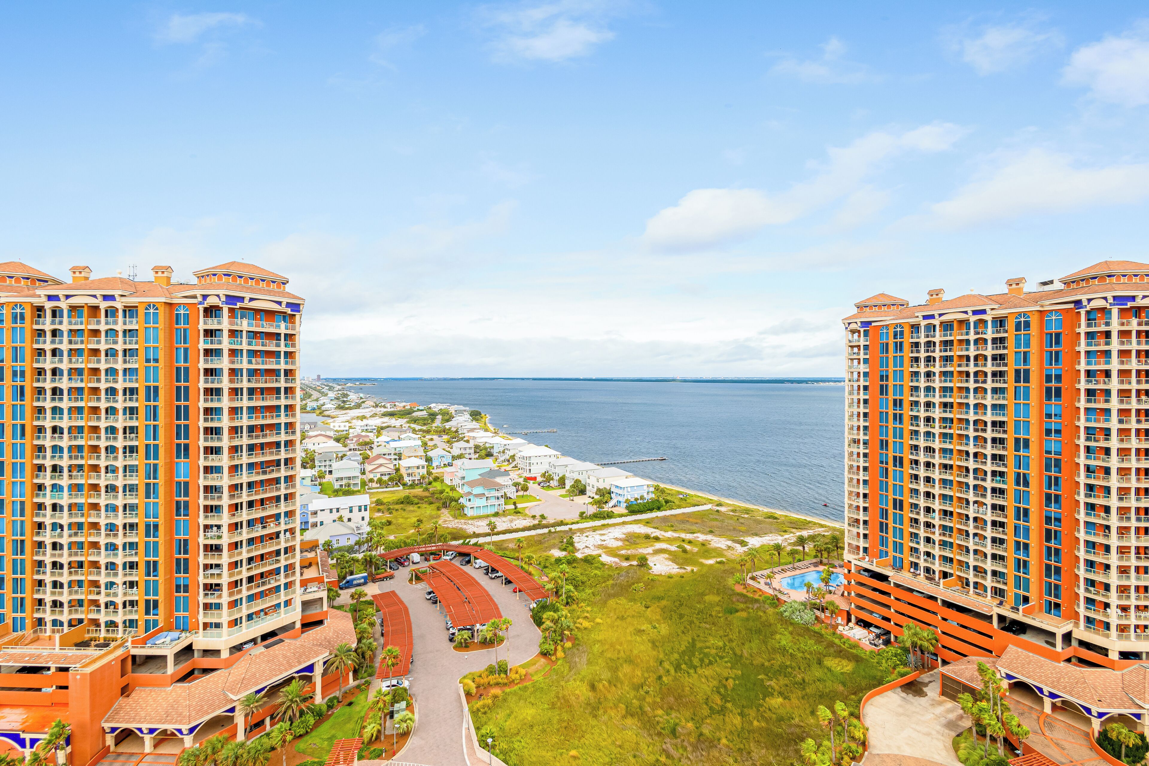 A high-rise hotel with multiple balconies, a marina, and a beach view.