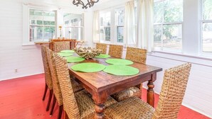 A dining room with a wooden table, wicker chairs, and a chandelier. - Coastal Soul Cottage | Pet Friendly, Fenced Yard (Tybee Island)