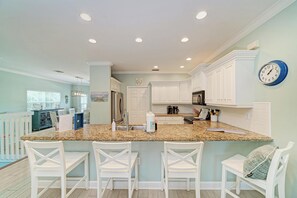 A kitchen with white cabinets, a granite countertop, and a clock on the wall.