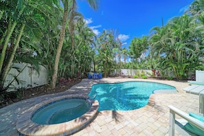 Un jardin avec une piscine, un jacuzzi et une végétation tropicale luxuriante.