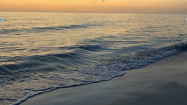 Una playa con olas tranquilas y cielo despejado.