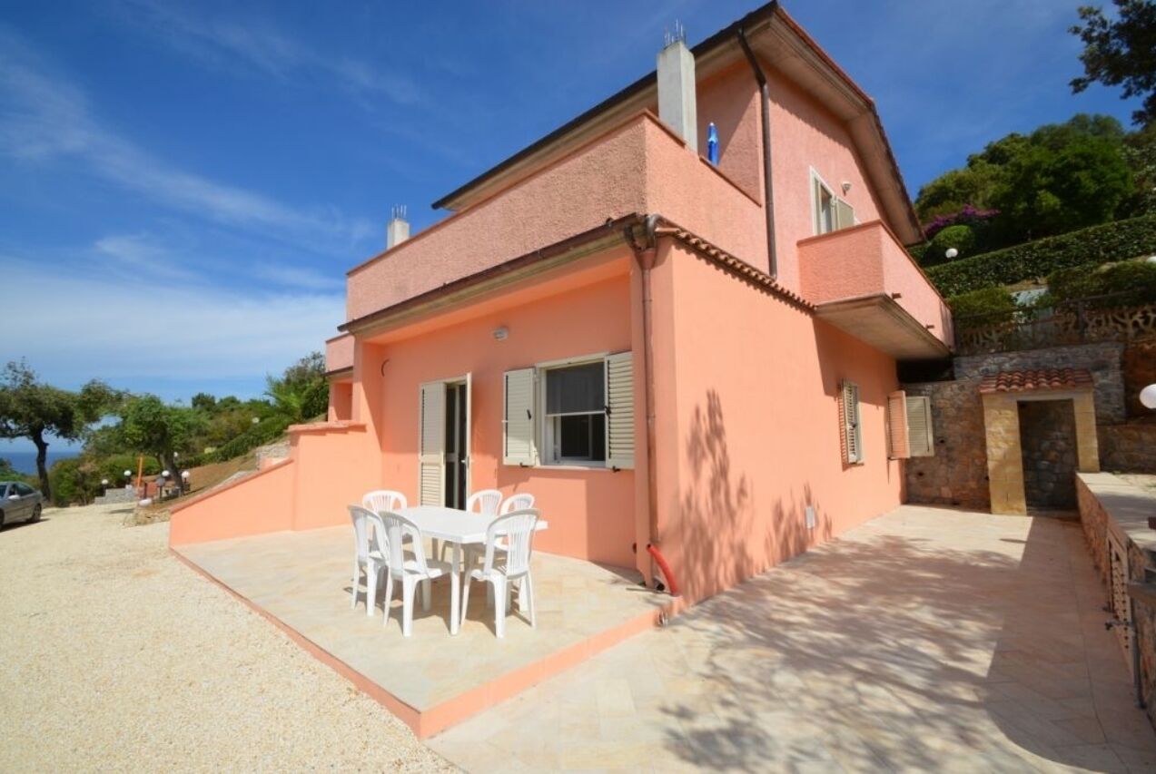A two-story house with a patio area featuring a table and chairs.