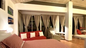 Ein Schlafzimmer mit einem großen Bett, einem roten Sofa, einem Sessel und einem kleinen Tisch.