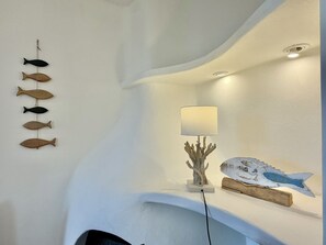 A room with a curved ceiling, a wall-mounted fish decoration, a table lamp, and a decorative piece resembling a fish.