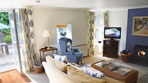 Ein Wohnzimmer mit Sofa, Sessel, Fernseher und Kamin.