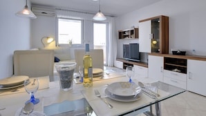 A modern dining area with a glass table, white plates, and a bottle of wine.
