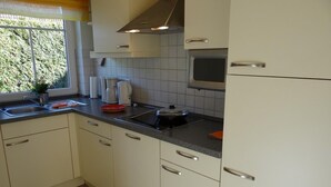 A kitchen with white cabinets, a black countertop, a stove, and a window with a view of greenery. - Stylish and native: The tastefully furnished semi-detached house provides a (Carolinensiel)