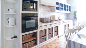 A kitchen with white cabinets, a tiled backsplash, and a dining area with a striped tablecloth.