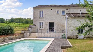 A stone building with a swimming pool and wooden deck.