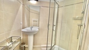 A modern bathroom with a glass-enclosed shower, a pedestal sink, and a towel rack. - Bristol (Cannes)