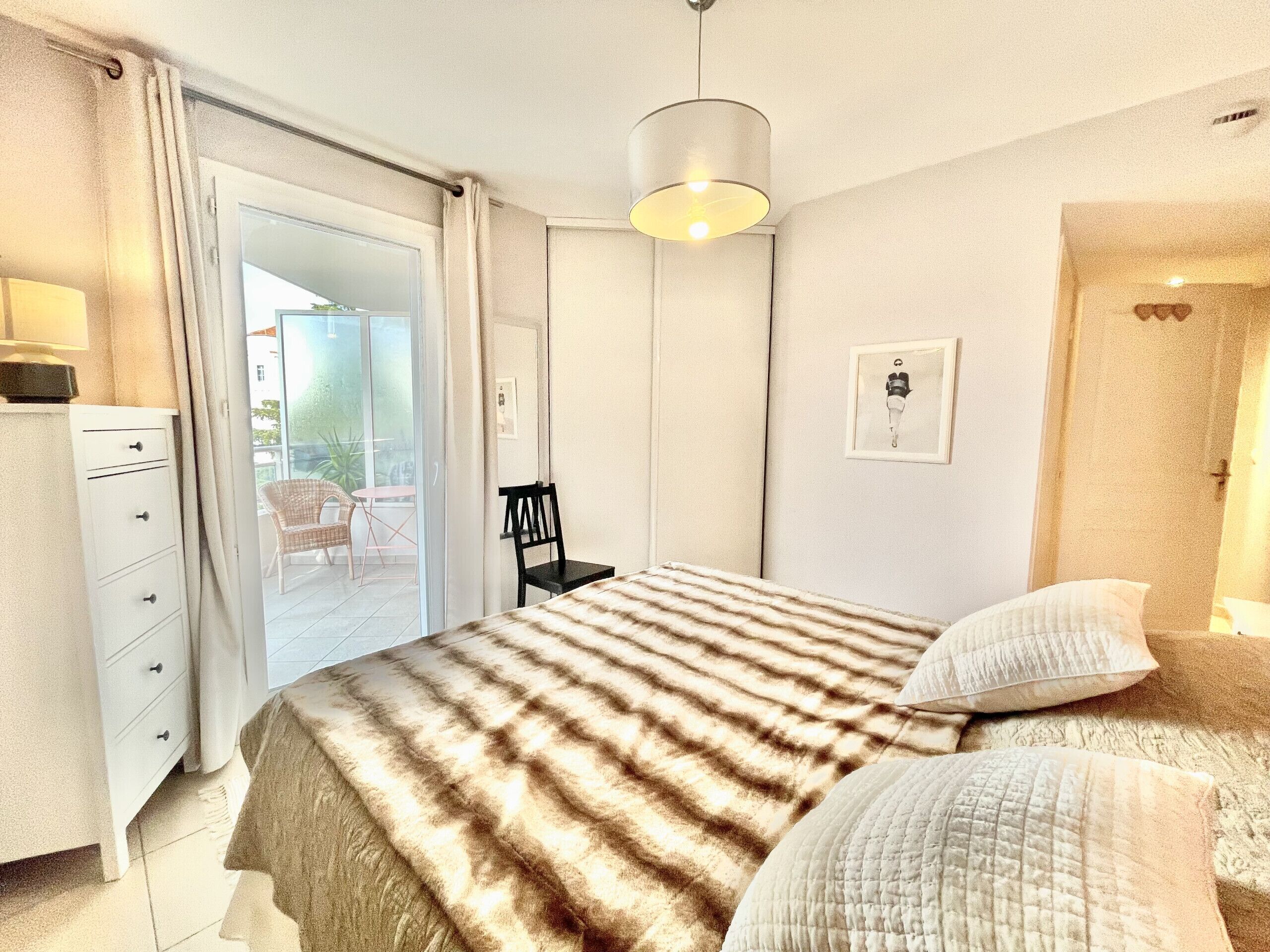 Une chambre à coucher comprenant un lit, une chaise, un bureau et une porte donnant sur un balcon.