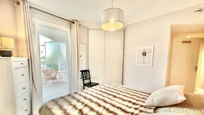 A bedroom with a bed, a chair, a desk, and a door leading to a balcony. - Bristol (Cannes)
