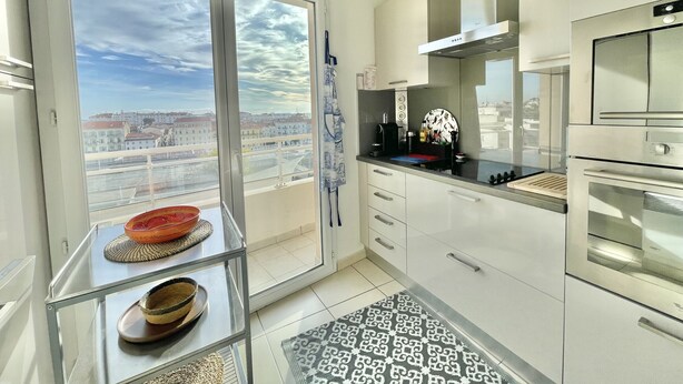 A modern kitchen with a large window, stainless steel appliances, and a view of the city. - Bristol (Cannes)