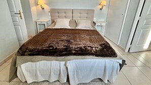 A large bed with a brown and white bedspread, two bedside tables with lamps, and a light-colored headboard. - Bristol (Cannes)