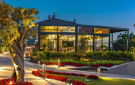 A modern hotel with a well-maintained garden, a lobby area, and a building with multiple windows.