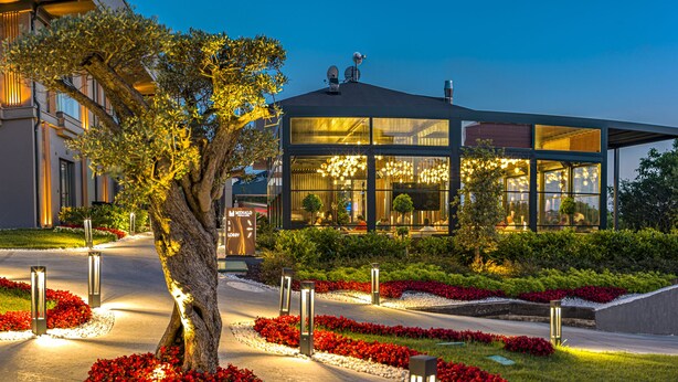 A modern hotel with a well-maintained garden, a lobby area, and a building with multiple windows. - Menalo Hotel Premium Istanbul Airport (Arnavutköy)
