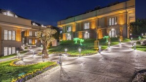 A modern hotel with a well-lit driveway and landscaped garden. - Menalo Hotel Premium Istanbul Airport (Arnavutköy)
