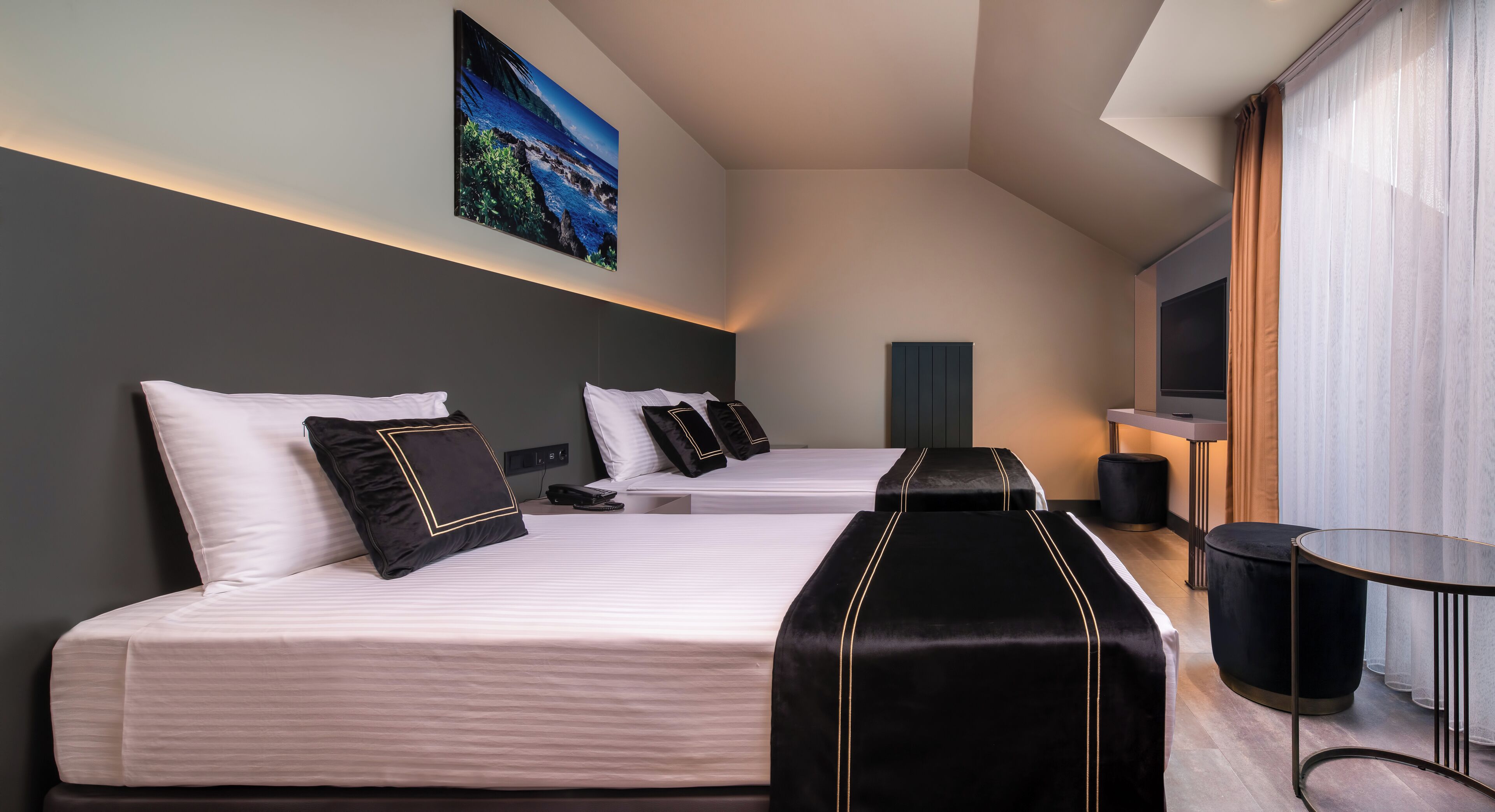 Una habitación de hotel moderna con dos camas, un televisor de pantalla plana y un gran ventanal con cortinas.
