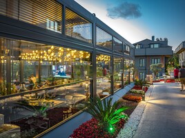 Un edificio moderno con amplios ventanales, asientos al aire libre y un interior bien iluminado.