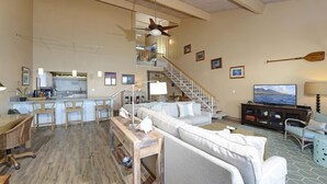 A spacious living area with a large sofa, a dining table, and a kitchen in the background.