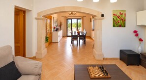 Un vaste espace de vie comprenant une table à manger, un jeu d’échecs et un canapé.
